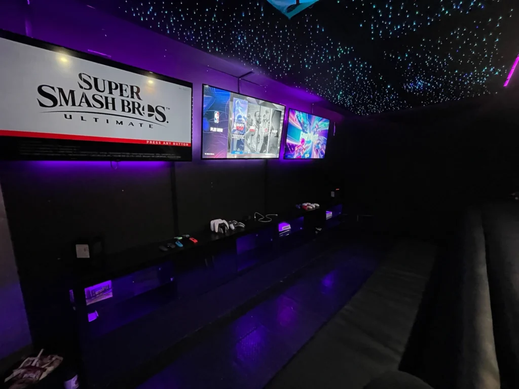 Inside the Gamers Getaway gaming theatre: wall-mounted screens running Super Smash Bros. Ultimate, with seating for kids