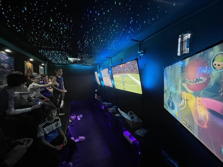 Kids playing games side by side along the screens in the video game truck