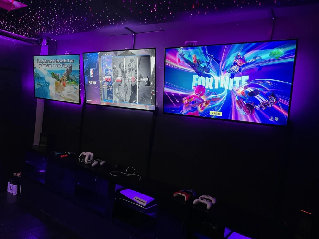 Fortnite and other multiplayer games running across the screens inside the Gamers Getaway trailer