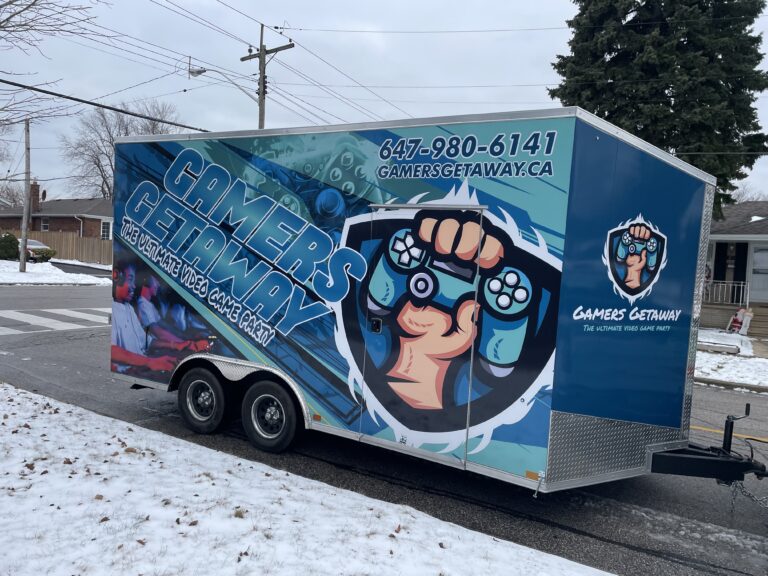 Side view of the wrapped Gamers Getaway video game trailer parked at a party