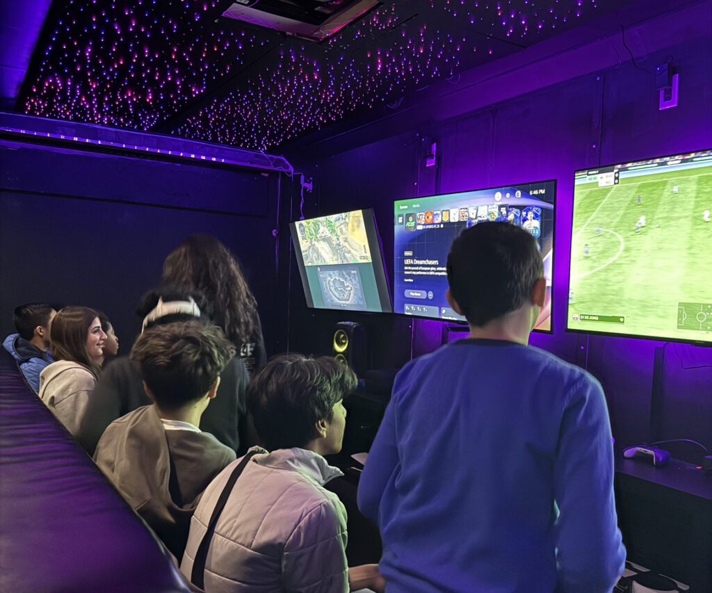 Teens playing a soccer video game together inside the Gamers Getaway gaming trailer