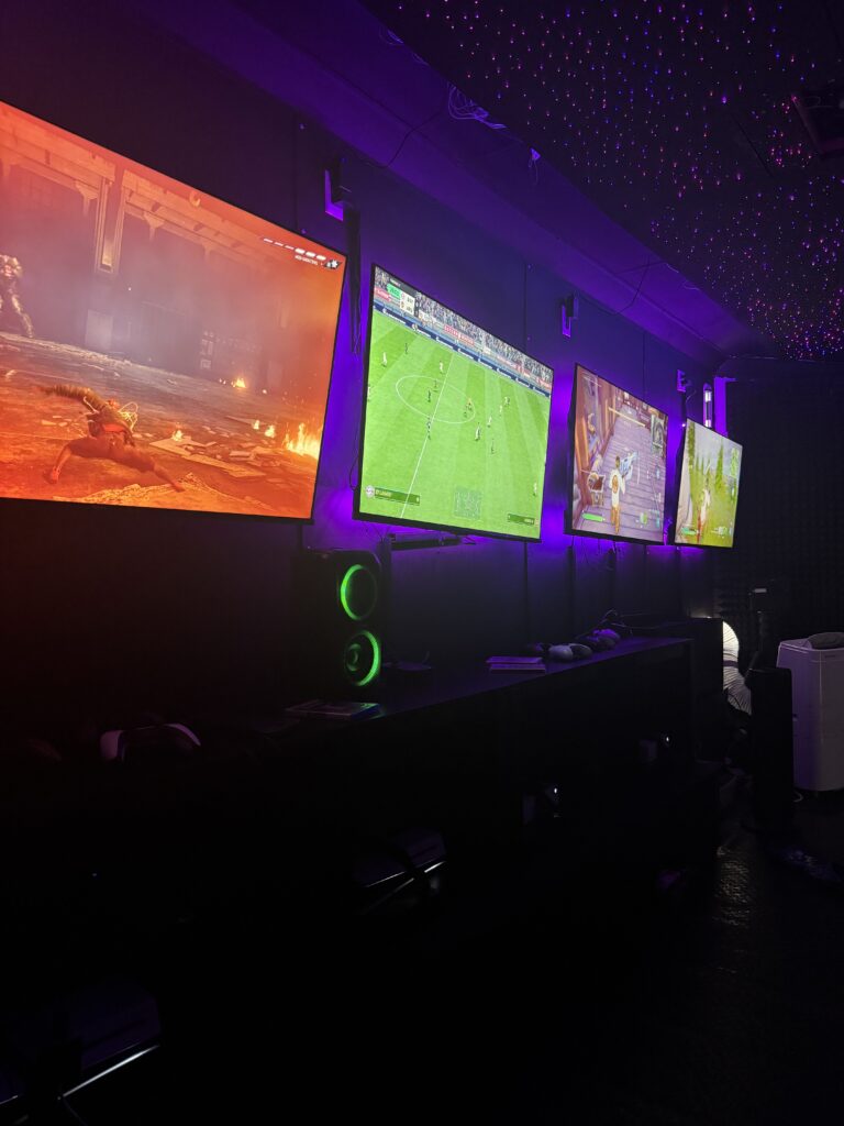 Inside the Gamers Getaway gaming theatre: wall-mounted screens with games running under purple lighting