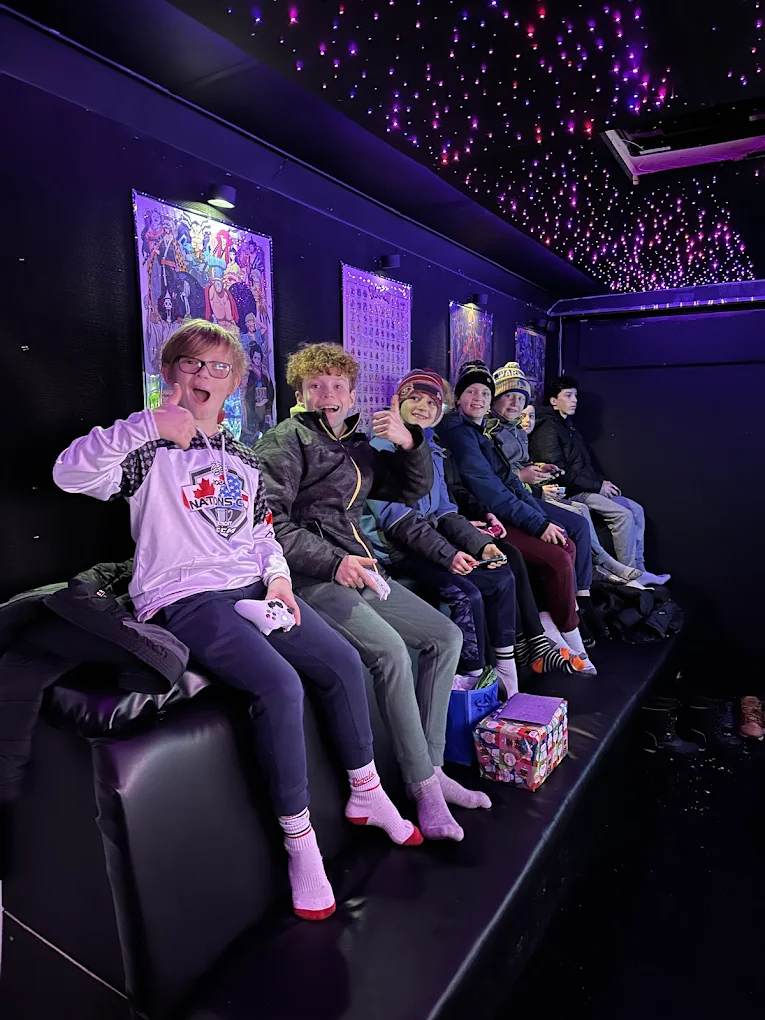 A group of kids grinning on the bench seating inside the Gamers Getaway truck at a birthday party