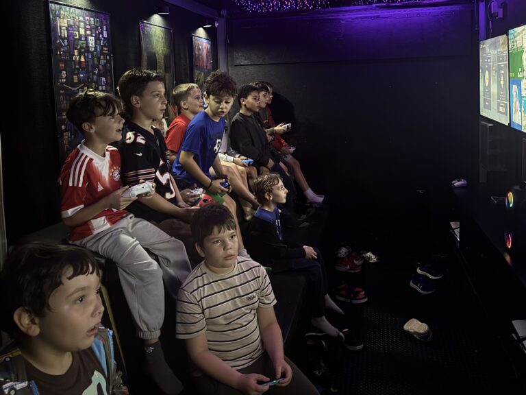 Group of kids playing video games on the benches inside the gaming trailer